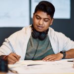 Shot Of A Young Architect Writing In A Notebook At His Desk In A Modern Office