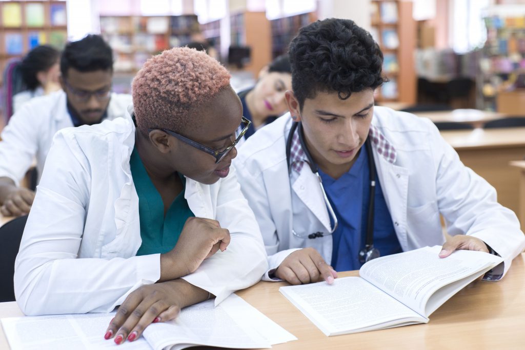 A Group Of Young Multinational Races, Medical Students. They Write The Exam While Sitting At The Table.