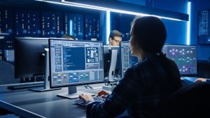 Smart Female It Programer Working On Desktop Computer In Data Center System Control Room. Team Of Young Professionals Doing Code Programming