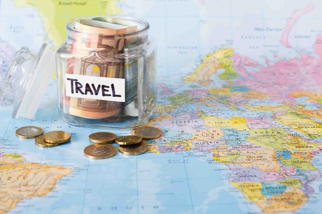 Traveling Budget Concept. Money Saved For Vacation In Glass Jar On Map Background