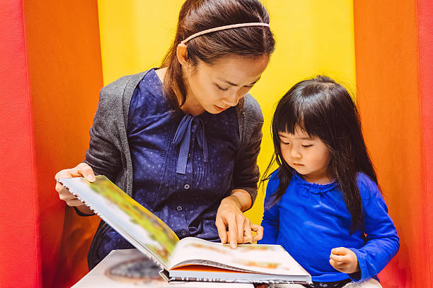 Pretty Young Mom Reading Story Books With Lovely Little Girl In The Bookstore