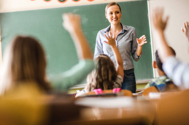 Happy Female Teacher Asked A Question During A Class At Elementary School.