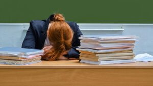 Woman Teacher Sleeps Resting Her Head At School Desk, Copy Space